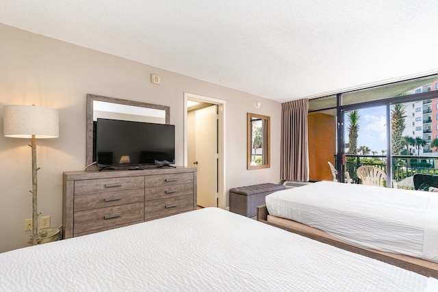 bedroom with floor to ceiling windows, a textured ceiling, and access to outside