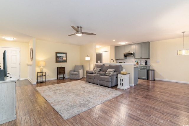 living room featuring ceiling fan, dark wood-type flooring, and sink