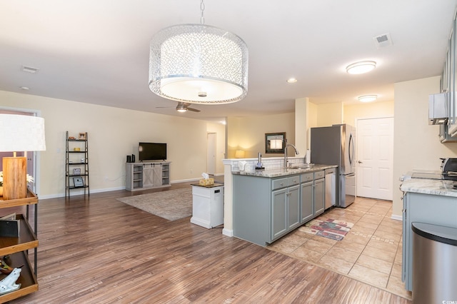 kitchen featuring sink, light hardwood / wood-style flooring, ceiling fan, stainless steel fridge, and decorative light fixtures