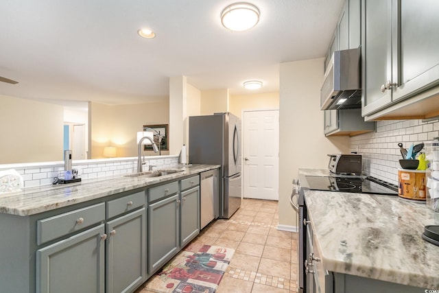 kitchen with appliances with stainless steel finishes, light stone counters, gray cabinetry, sink, and light tile patterned floors