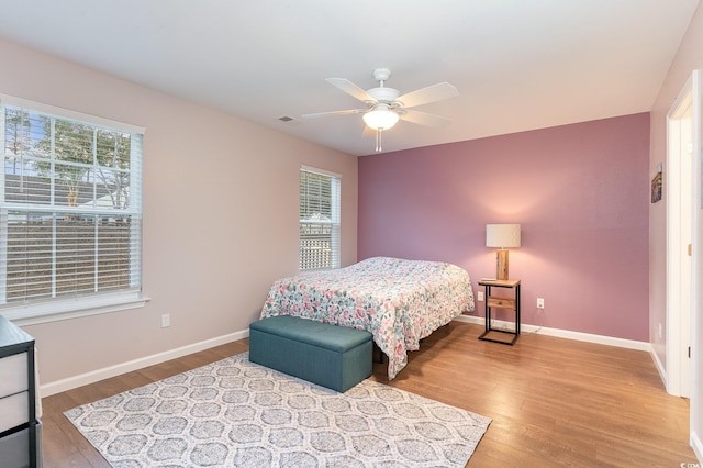 bedroom featuring multiple windows, ceiling fan, and light wood-type flooring