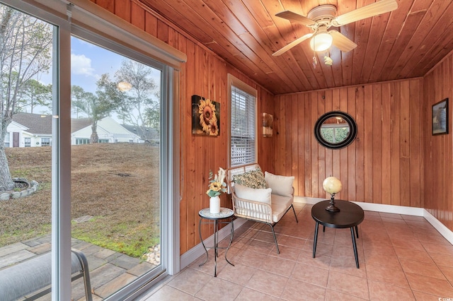 sitting room with a wealth of natural light, light tile patterned flooring, wooden ceiling, and wooden walls