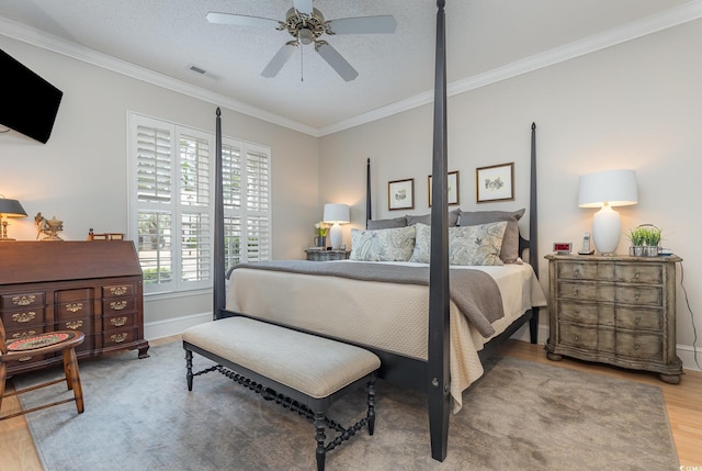 bedroom featuring a textured ceiling, hardwood / wood-style flooring, ceiling fan, and ornamental molding