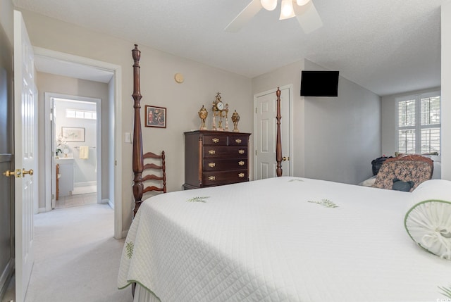 bedroom with ceiling fan, ensuite bathroom, a textured ceiling, and light carpet