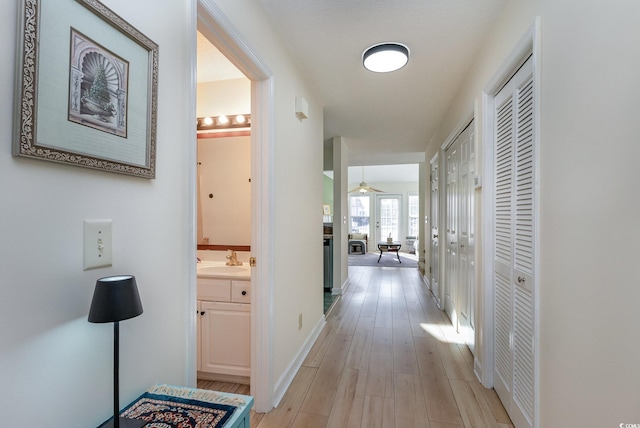 corridor featuring sink and light hardwood / wood-style floors