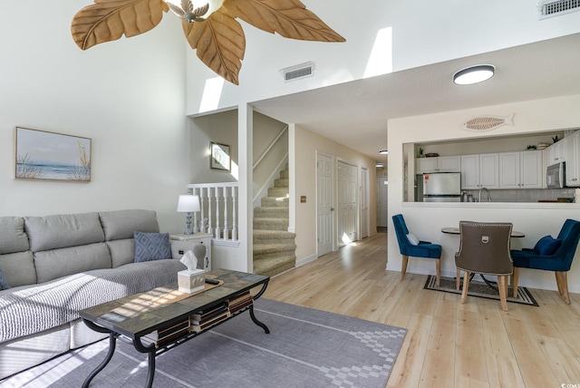 living room featuring a towering ceiling and light hardwood / wood-style flooring