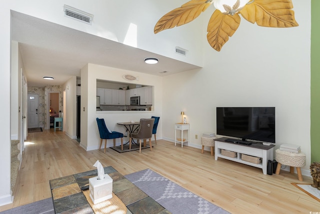 living room featuring a high ceiling and light hardwood / wood-style floors