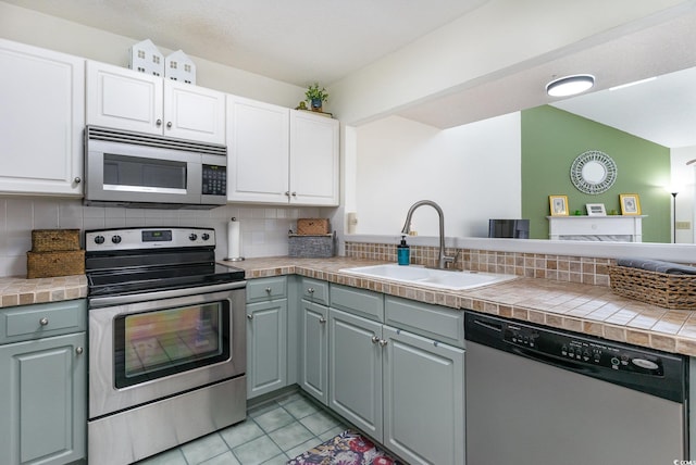 kitchen featuring gray cabinetry, white cabinets, sink, appliances with stainless steel finishes, and tasteful backsplash