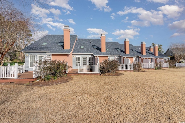 rear view of house featuring a lawn and a deck