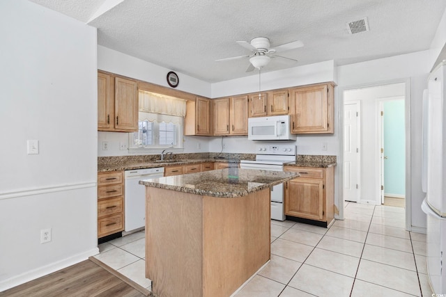703 Gleneagles Dr, Myrtle Beach, SC 29588 - kitchen with a textured ceiling, dark stone countertops, a center island, and white appliances