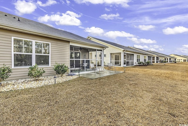 back of property featuring a lawn, a patio area, and a sunroom