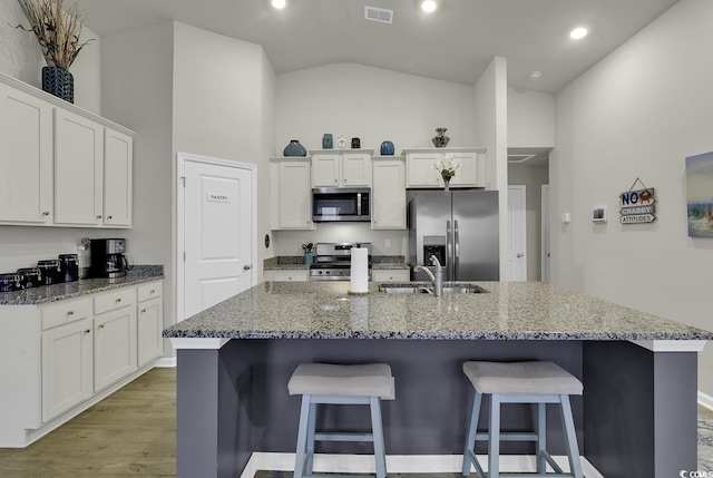 kitchen featuring white cabinets, stainless steel appliances, and an island with sink