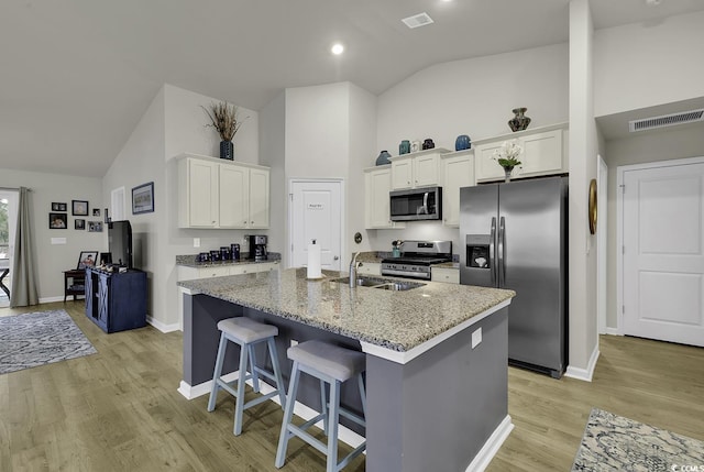 kitchen featuring white cabinetry, an island with sink, light stone countertops, and appliances with stainless steel finishes