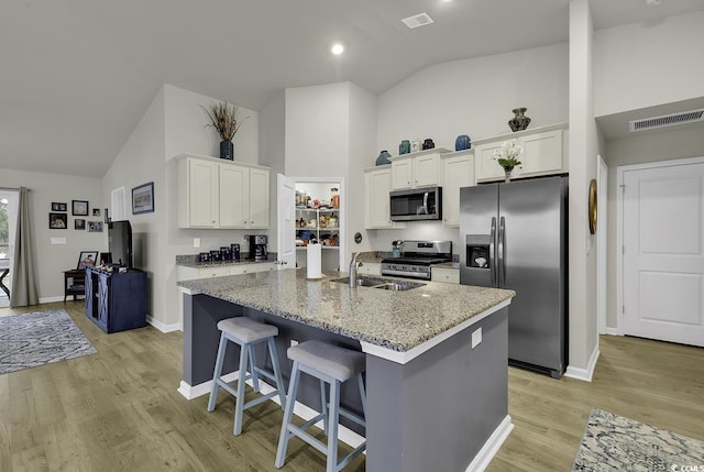 kitchen featuring light stone countertops, white cabinetry, an island with sink, and stainless steel appliances