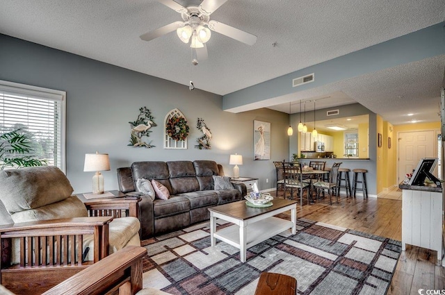 living room with ceiling fan, hardwood / wood-style floors, and a textured ceiling