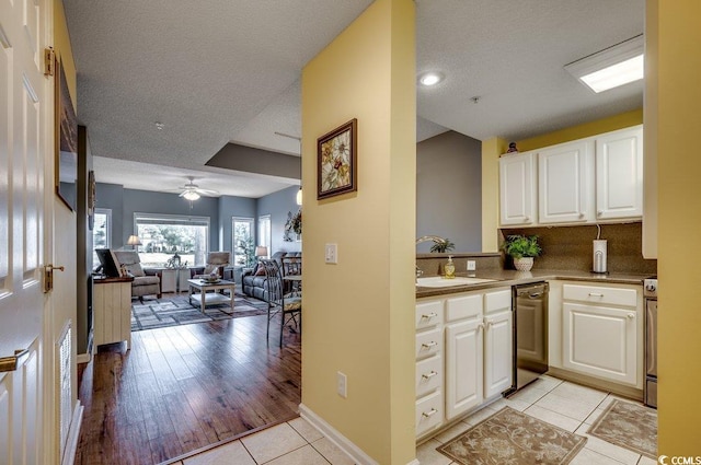 kitchen featuring a textured ceiling, ceiling fan, sink, light tile patterned floors, and white cabinetry