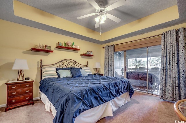 carpeted bedroom with a textured ceiling, access to outside, a raised ceiling, and ceiling fan