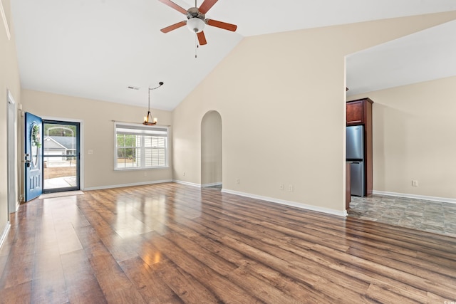 spare room featuring baseboards, high vaulted ceiling, wood finished floors, and ceiling fan with notable chandelier