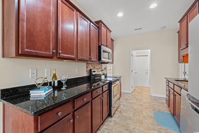 kitchen with stainless steel appliances, visible vents, baseboards, decorative backsplash, and dark stone countertops