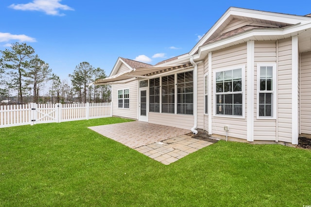 rear view of house with a yard, a patio area, fence, and a gate