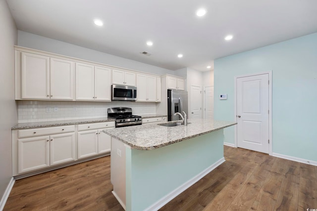 kitchen with white cabinets, sink, an island with sink, appliances with stainless steel finishes, and wood-type flooring