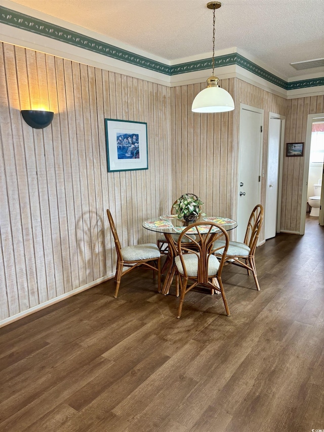 dining area with a textured ceiling and dark wood-type flooring