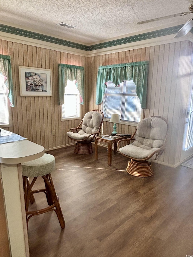 living area featuring hardwood / wood-style floors, ceiling fan, and a textured ceiling