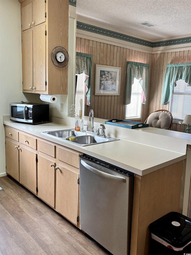 kitchen with light brown cabinetry, a textured ceiling, stainless steel appliances, sink, and light hardwood / wood-style flooring