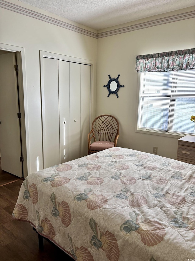 bedroom with a textured ceiling, dark hardwood / wood-style floors, and ornamental molding