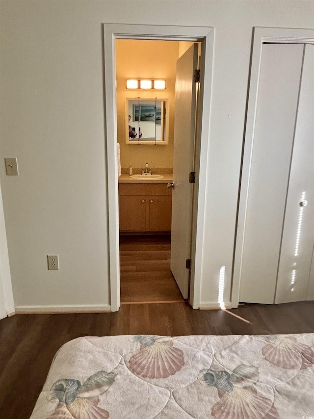 bedroom featuring ensuite bathroom, dark hardwood / wood-style flooring, sink, and a closet