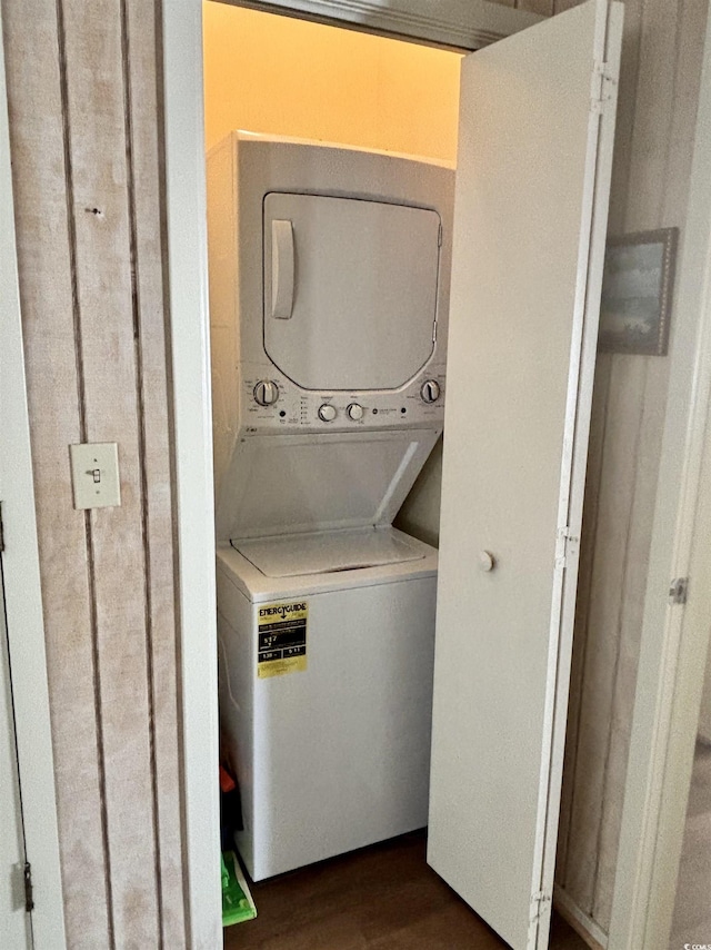 laundry area with dark wood-type flooring and stacked washer and clothes dryer