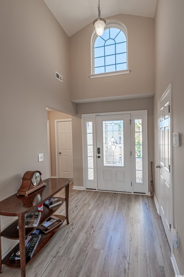 foyer entrance featuring high vaulted ceiling and light wood-type flooring