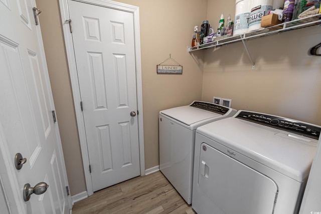 laundry room with washing machine and dryer and light hardwood / wood-style floors