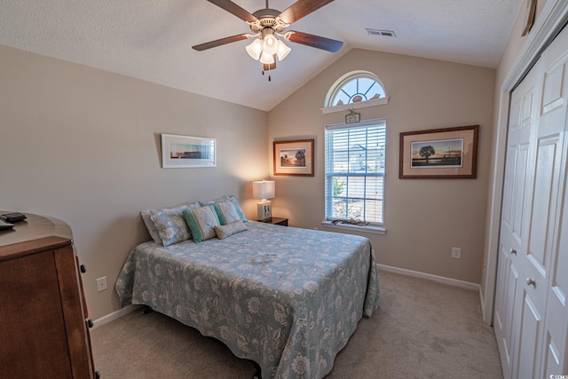 carpeted bedroom with ceiling fan, lofted ceiling, and a closet