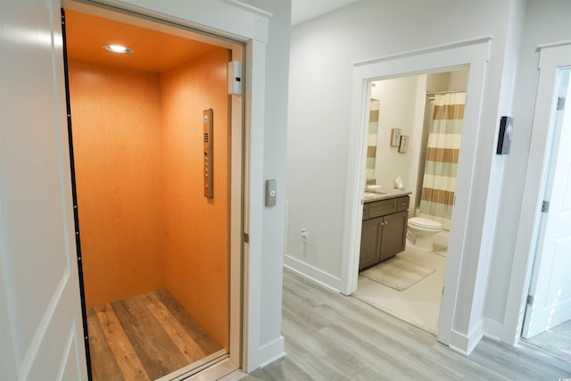 hall featuring elevator and light hardwood / wood-style flooring