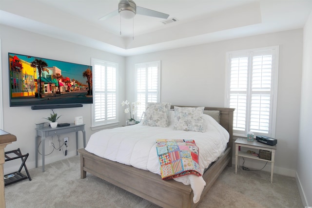 bedroom with a tray ceiling, multiple windows, and ceiling fan