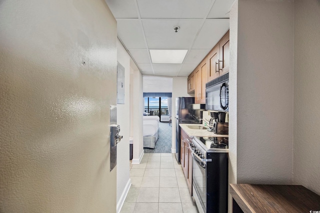 kitchen with light tile patterned flooring, stainless steel range with electric stovetop, sink, and a paneled ceiling