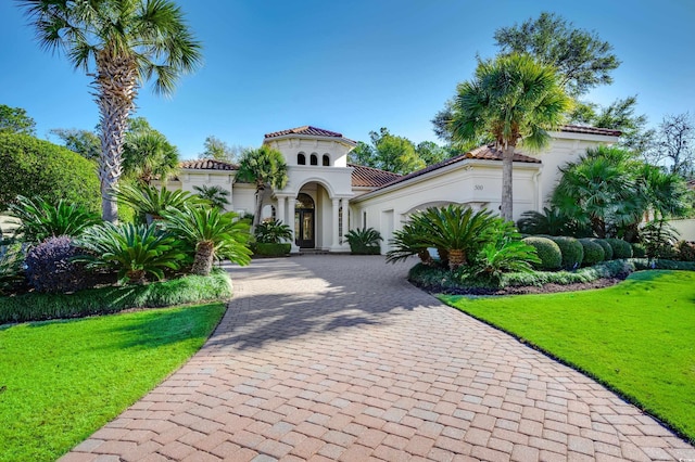 mediterranean / spanish-style house featuring a front yard and a garage