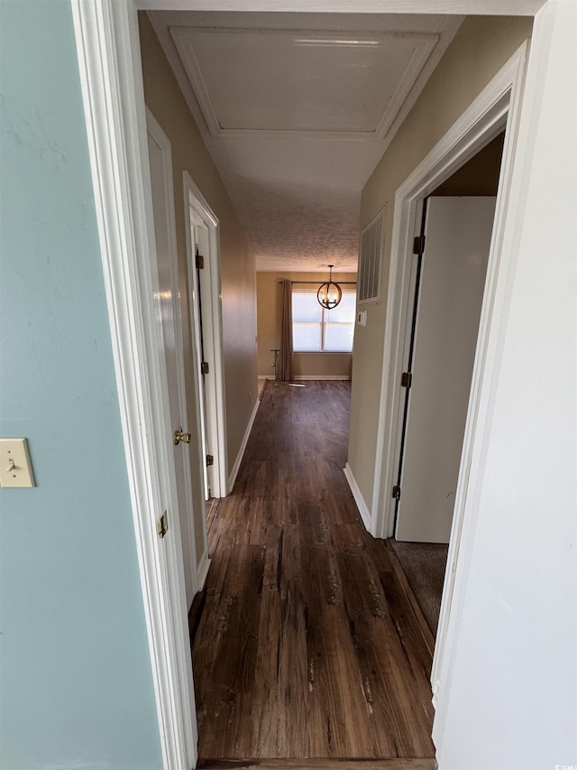 corridor with dark hardwood / wood-style floors and a textured ceiling