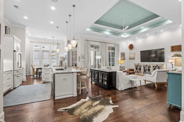 kitchen featuring high end white refrigerator, a center island with sink, a kitchen breakfast bar, pendant lighting, and white cabinets