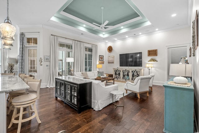 living room with ornamental molding, ceiling fan, dark hardwood / wood-style flooring, and a tray ceiling