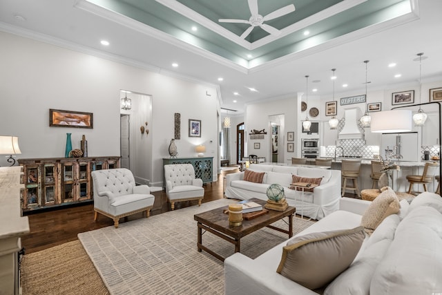 living room featuring ornamental molding, dark hardwood / wood-style floors, ceiling fan, and a tray ceiling