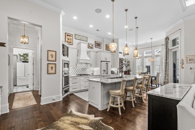 kitchen featuring a large island, decorative light fixtures, custom exhaust hood, and white cabinets