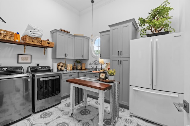 laundry area with ornamental molding, sink, washing machine and dryer, and light tile patterned floors