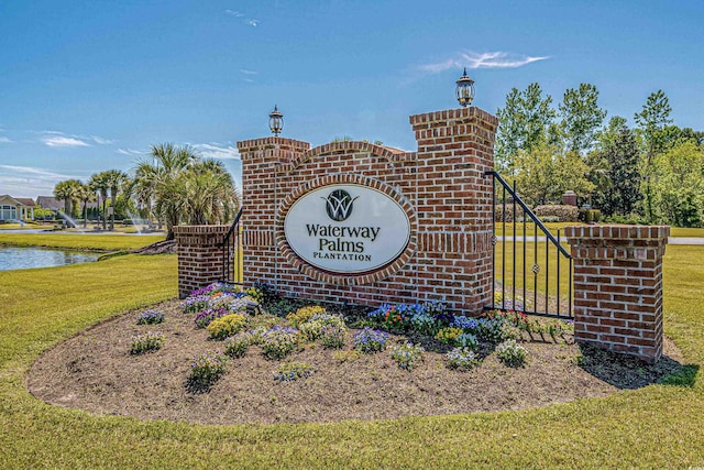 community sign featuring a water view and a lawn