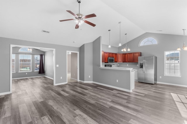 unfurnished living room featuring wood-type flooring, ceiling fan with notable chandelier, and high vaulted ceiling