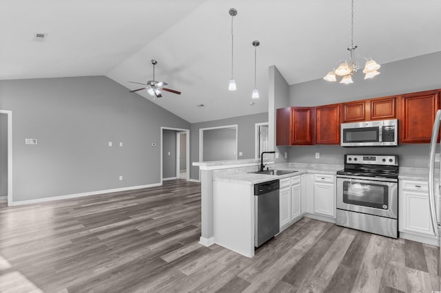 kitchen with kitchen peninsula, ceiling fan with notable chandelier, stainless steel appliances, sink, and decorative light fixtures