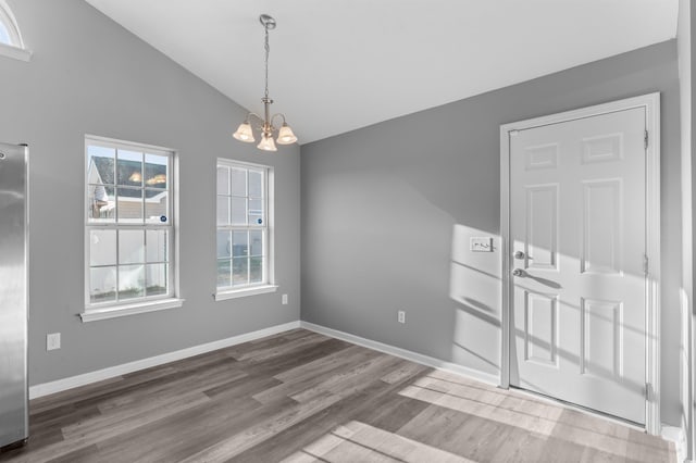 unfurnished dining area featuring hardwood / wood-style floors, lofted ceiling, and a notable chandelier