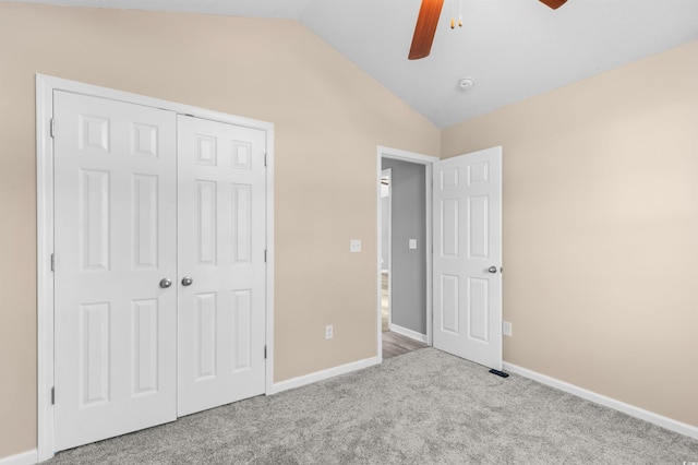 unfurnished bedroom with ceiling fan, a closet, light carpet, and lofted ceiling