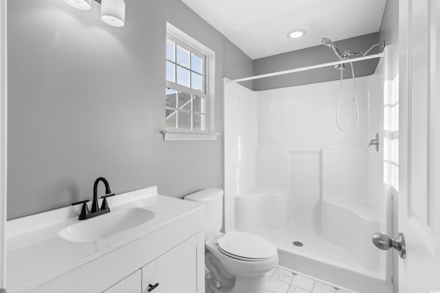 bathroom with tile patterned floors, toilet, vanity, and walk in shower